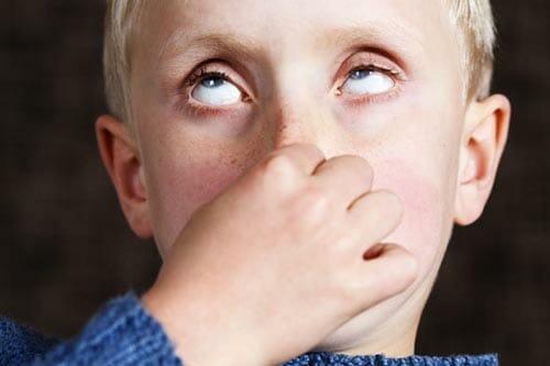 Little blonde boy holding breath by plugging his nose