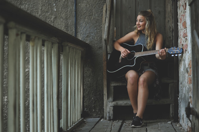 Young woman playing acoustic guitar on wooden steps