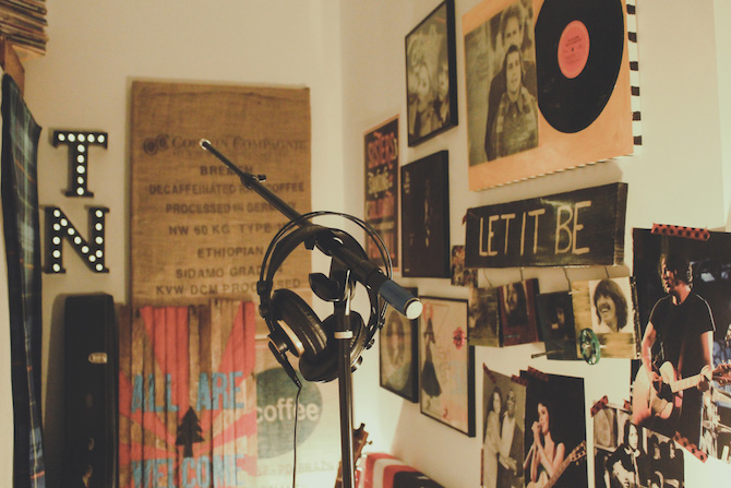 headphones hanging on a mic stand with music posters on the walls