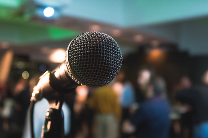 A dynamic microphone on a stage with people in the background