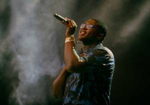 Young african american man singing into a microphone with a gold watch