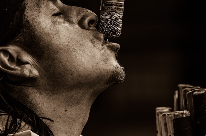 Sepia toned image of a singer close up on a microphone